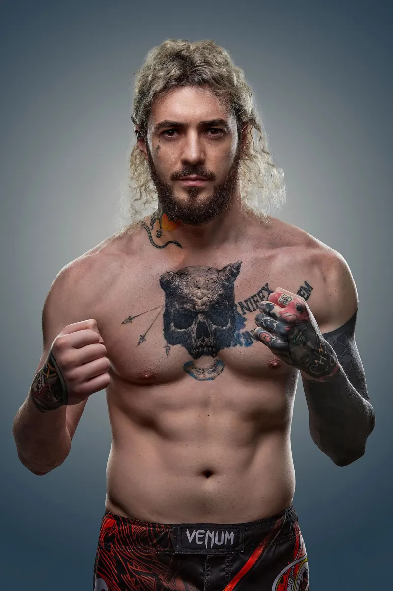 Studio portrait of a fighter with chest tattoos, fists raised