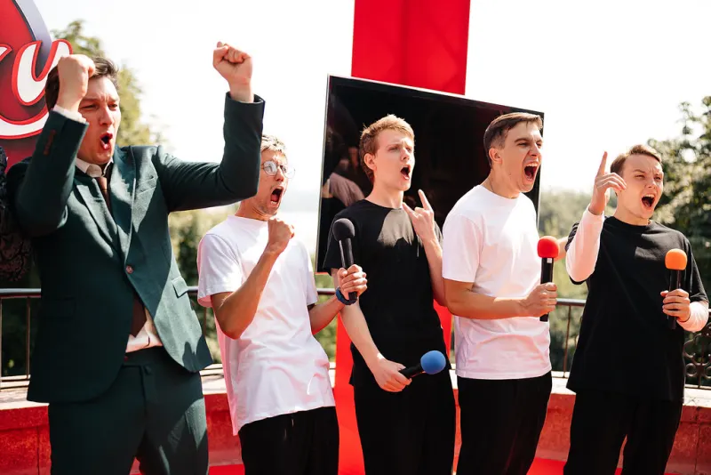 Group holding microphones cheering with raised fists in front of a branded backdrop