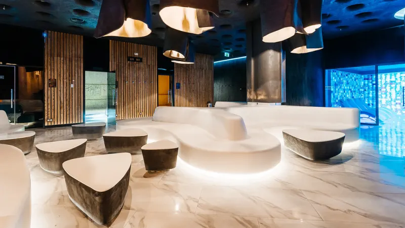 Curved white seating in a blue-lit bar with backlit panelling
