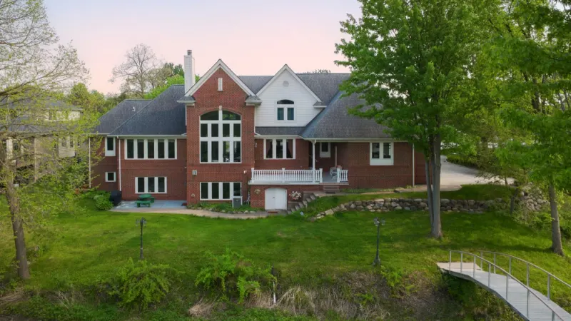 Red brick house with white trim among mature trees in spring
