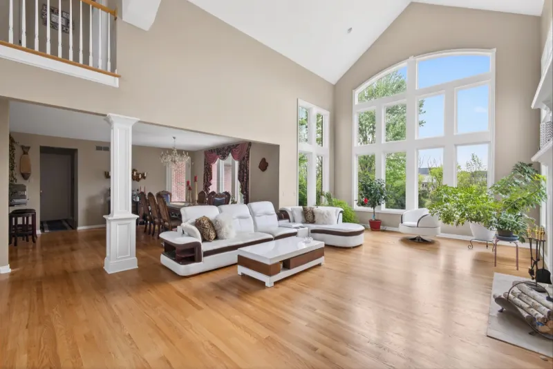 Vaulted great room with white columns, cream sofas and tall windows onto greenery