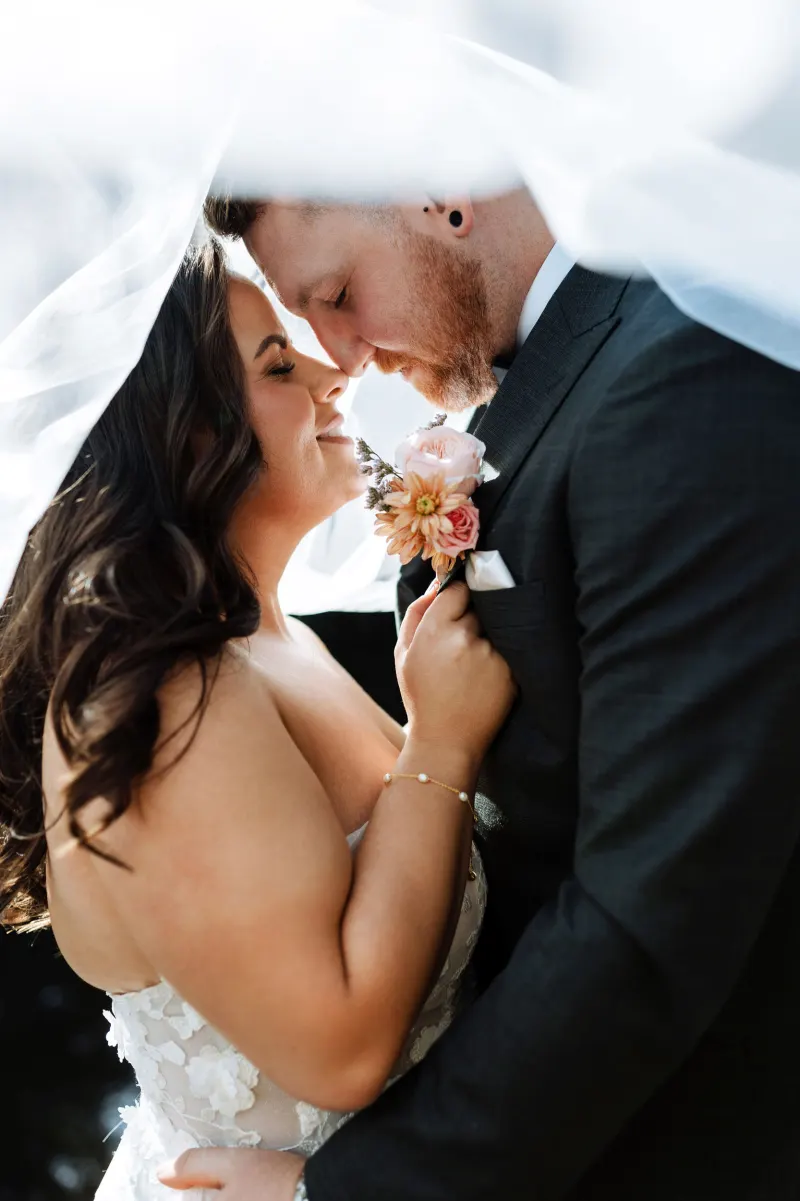 Bride and groom close together beneath the veil, lit low and warm