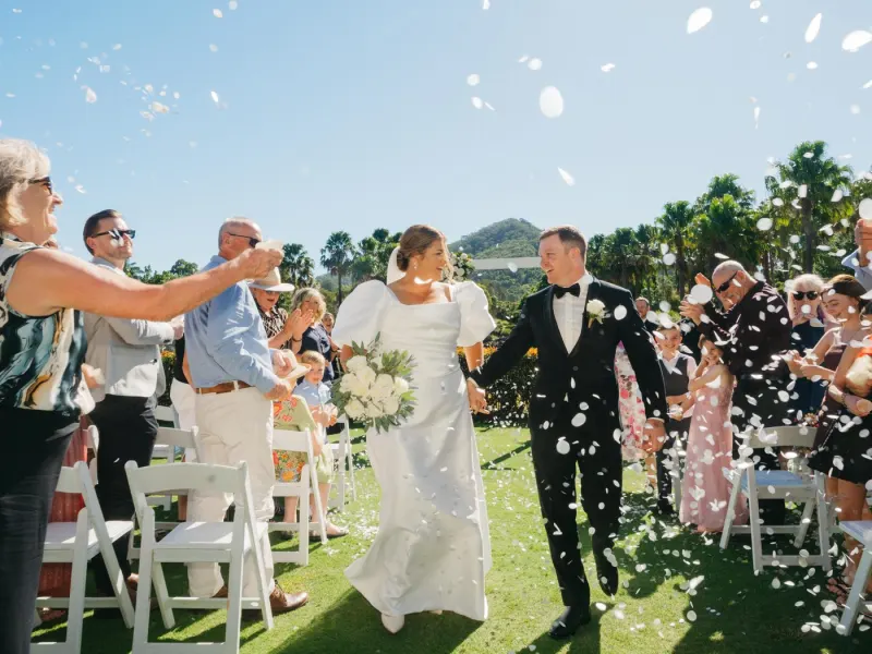 Confetti thrown over the couple as they walk back up the aisle between seated guests